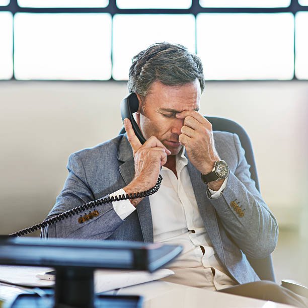 hot of a mature businessman looking stressed while talking on the phone hot of a mature businessman looking stressed while talking on the phone
